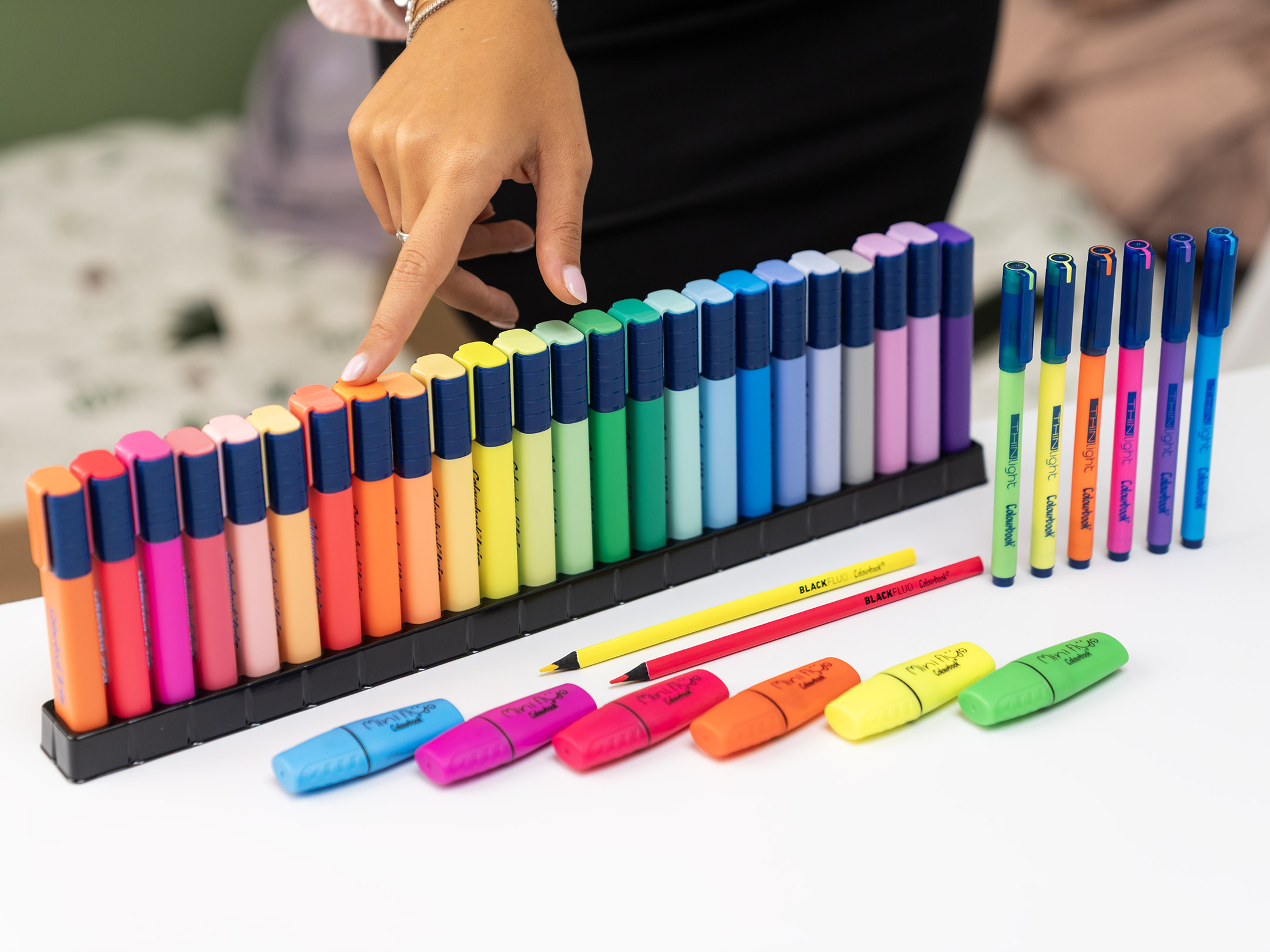 evidenziatore in una lunga fila ordinata di Colourbook Iris, disposti in gradazione cromatica: dal rosso al giallo, fino ai blu, viola e pastello. Sul tavolo sono presenti anche: Evidenziatori singoli sparsi, pronti all’uso, in colori fluo e brillanti. Penne Colourbook in vari colori coordinati. Matite colorate gialla e rossa, che aggiungono un tocco essenziale e vivace. L’immagine comunica l’idea di scelta e organizzazione attraverso il colore: ogni sfumatura diventa uno strumento per personalizzare appunti, schemi e idee, rendendo più facile la memorizzazione e più piacevole lo studio o il lavoro.